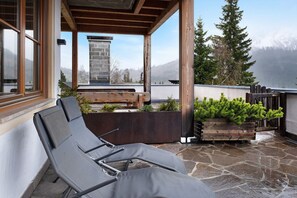 A covered outdoor seating area with lounge chairs, a wooden bench, and a planter with greenery. - Apartment "Angerle Alm Apt Similde B" with Private Terrace, Shared Garden & Wi-Fi (carezza Nova Levante)