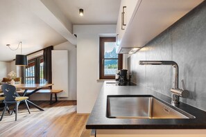 Una cocina moderna con una isla grande, electrodomésticos de acero inoxidable y vistas a montañas a través del ventanal.