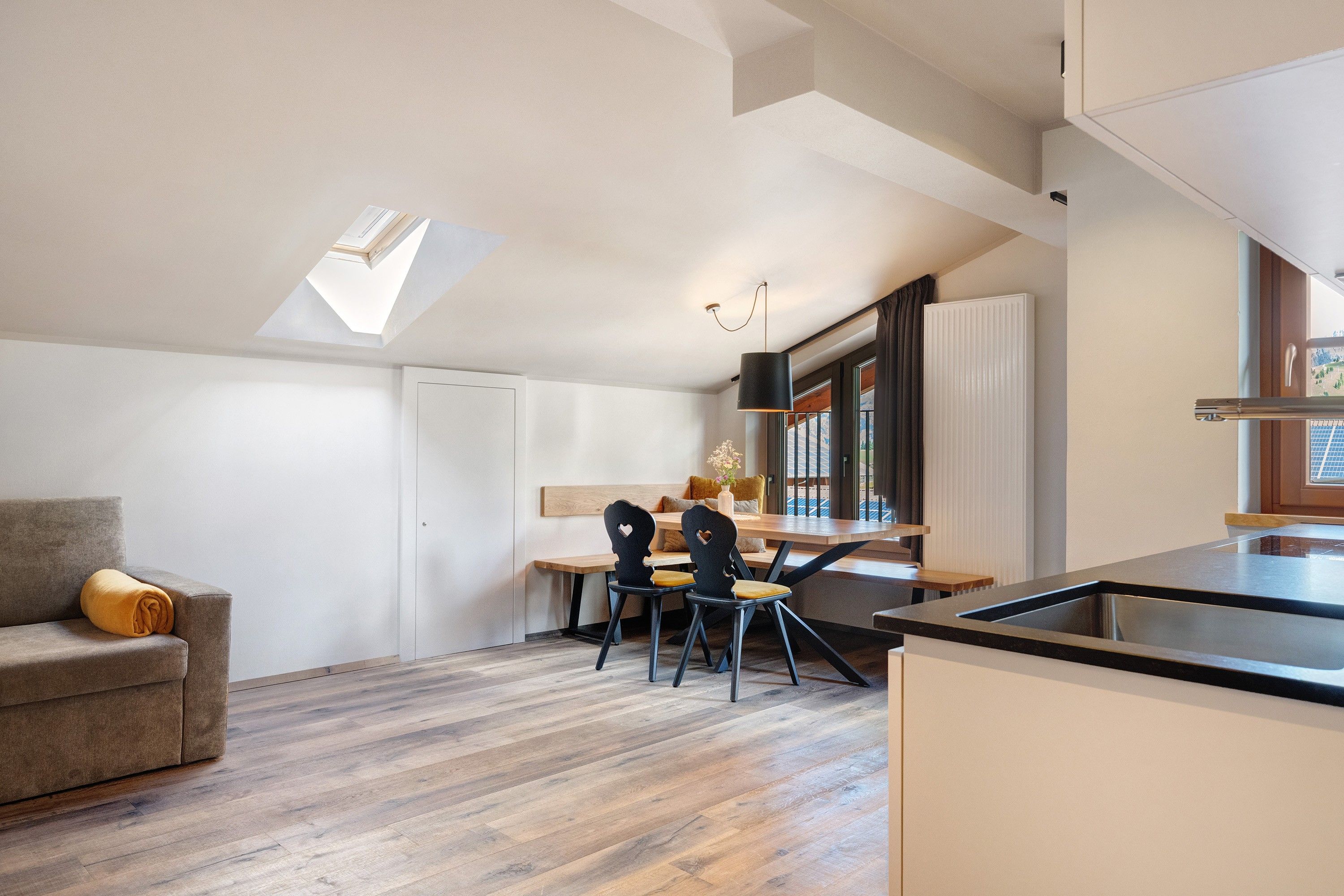 Une cuisine moderne avec un coin repas, une verrière et une vue sur l’extérieur.