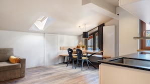 Une cuisine moderne avec un coin repas, une verrière et une vue sur l’extérieur.