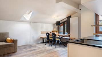 Une cuisine moderne avec un coin repas, une verrière et une vue sur l’extérieur.