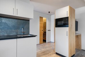 A modern kitchen with white cabinets, a black countertop, and a built-in microwave. - Apartment "Angerle Alm Apt Rosengarten" with Private Balcony, Shared Garden and Wi-Fi (carezza Nova Levante)