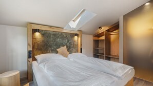 Une chambre à coucher moderne avec un puits de lumière, une tête de lit en bois et des étagères intégrées.