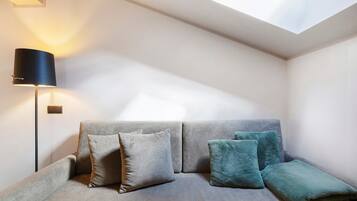 Una habitación moderna con sofá, almohadas, lámpara y tragaluz.