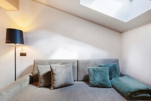 Une chambre moderne avec un canapé, des coussins, une lampe et une lucarne.