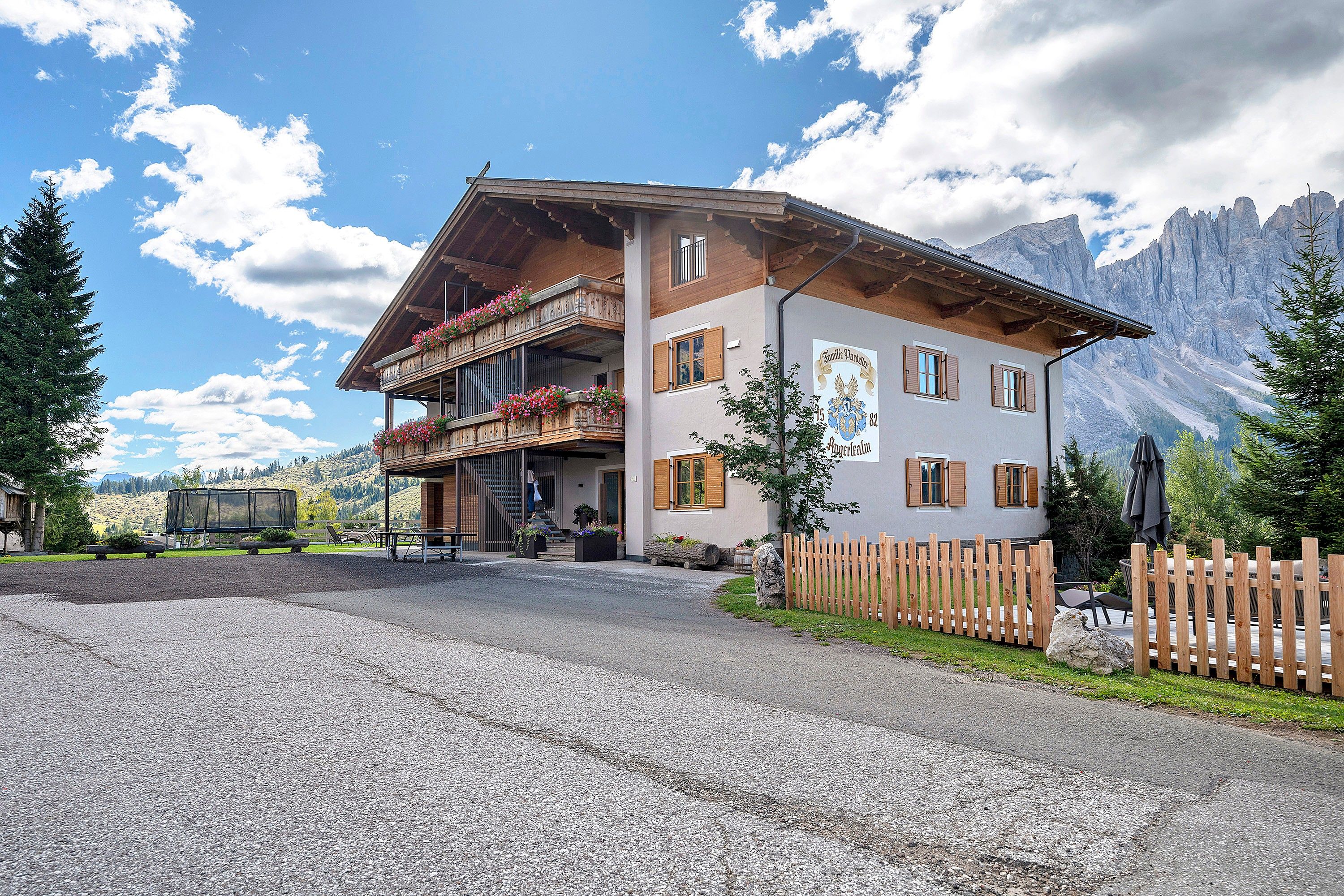 Ein zweistöckiges Gebäude mit Balkon, Holzzaun und Bergkulisse.
