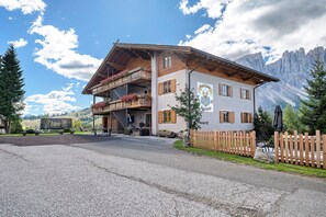 Un bâtiment à deux étages doté d’un balcon, d’une clôture en bois et surplombant un paysage montagneux.