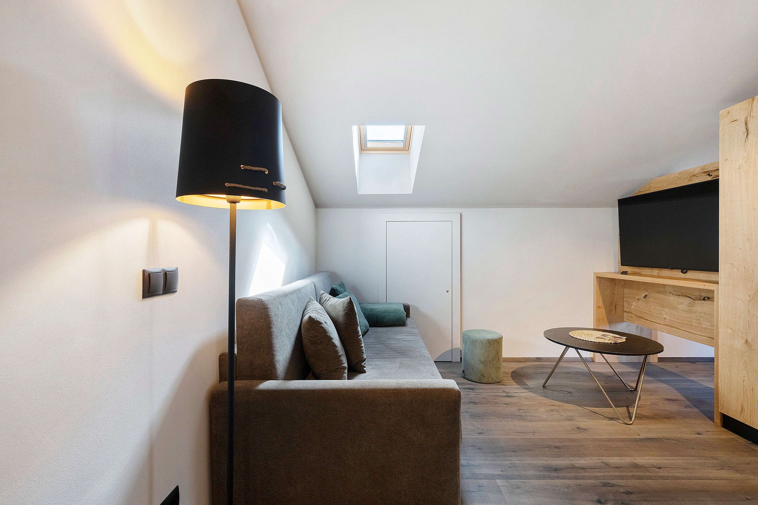 A cozy loft bedroom with a sofa, a small round table, and a TV.
