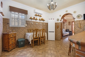 A compact kitchen with a dining area, a refrigerator, and a window with blinds.