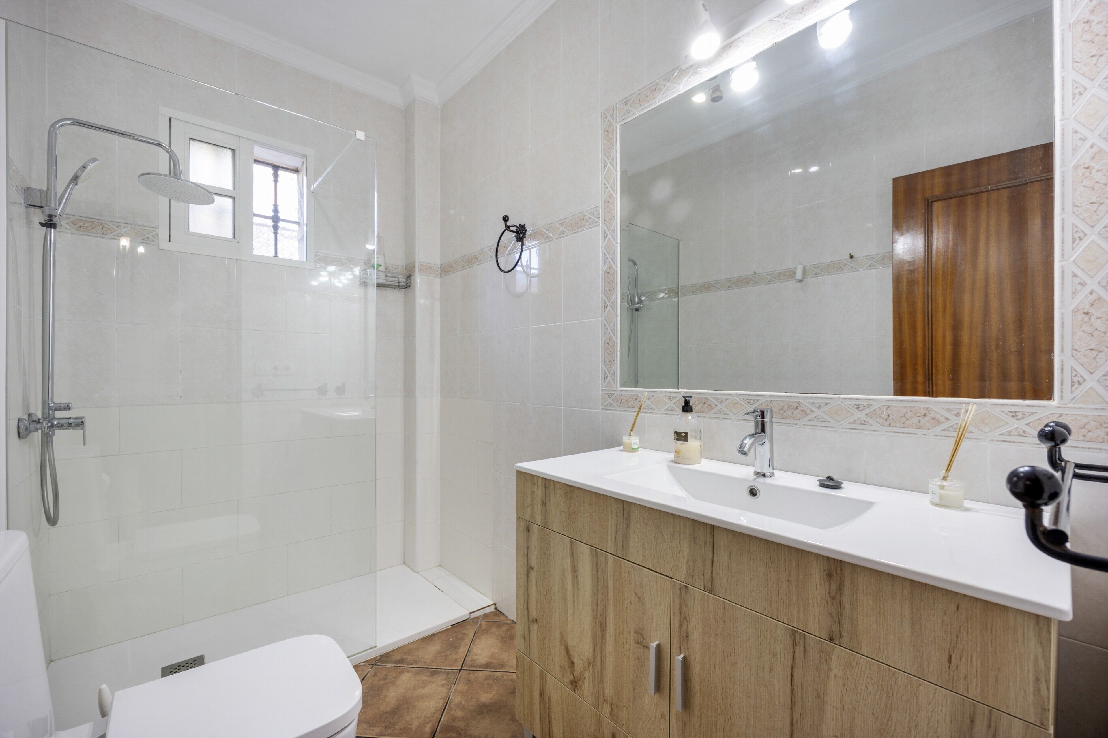 Ein Badezimmer mit Dusche, Toilette, Waschtisch und Spiegel.