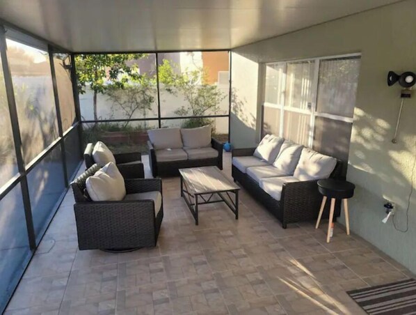Relax in this serene patio area with a wicker sofa, cushioned bench, and small table.
