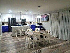 Enjoy meals in this kitchen with a stainless steel refrigerator, sink, and microwave, adjacent to a dining area with a table and chairs.