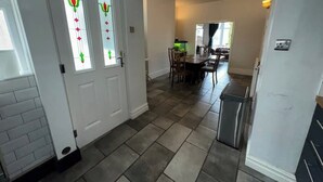 Uma cozinha ampla com área de refeições, com piso em azulejo e porta branca com painéis de vidro decorativos.