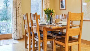 A dining area with a wooden table set for four, surrounded by wooden chairs with leather cushions. - 3 bedroom accommodation in Keswick (Keswick)