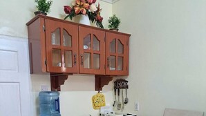 Une cuisine compacte avec des meubles en bois, une cuisinière à gaz, un évier et un distributeur d’eau.