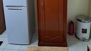 Une cuisine de taille réduite, avec un réfrigérateur blanc et un meuble en bois doté de portes en verre.