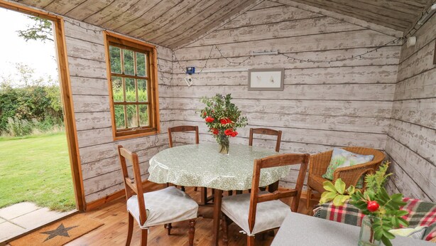 Um quarto acolhedor com decoração em madeira, uma mesa redonda com cadeiras, uma janela e vista para um pequeno jardim.