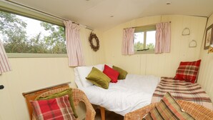 Une chambre confortable avec un lit, deux fauteuils en osier et une fenêtre avec des rideaux.