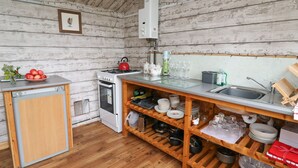 Une cuisine de taille réduite, équipée d’une cuisinière, d’un four et d’étagères en bois.