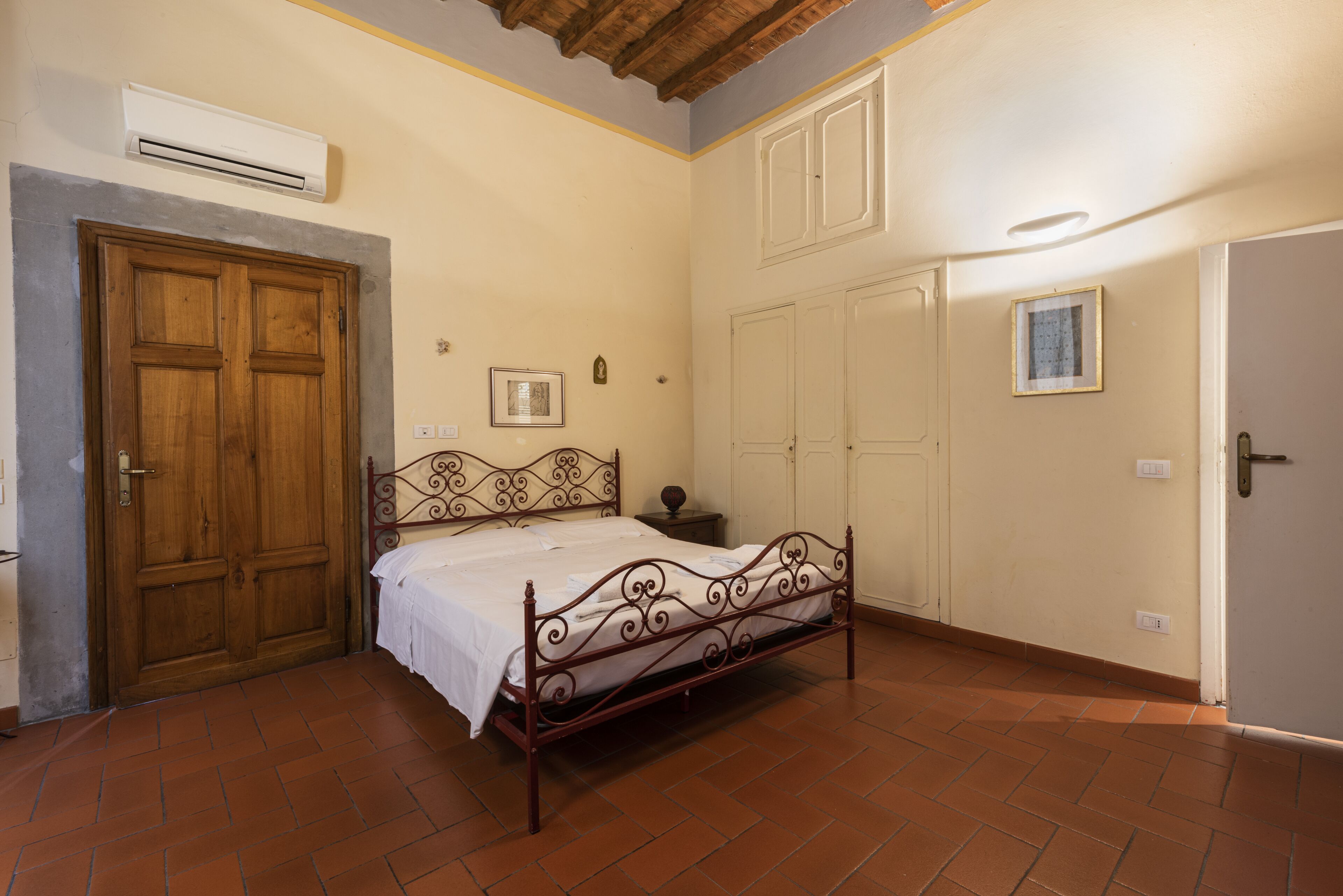 A bedroom with a metal bed frame, a wooden door, and a tiled floor.