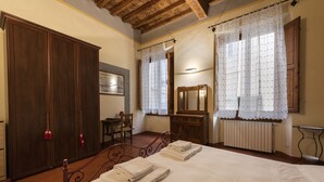 Quarto com cama grande, guarda-roupa de madeira, escrivaninha e espelho.