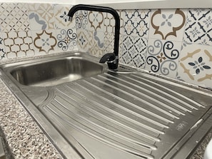 Sink set against a geometric-patterned backsplash, mounted on a granite countertop.