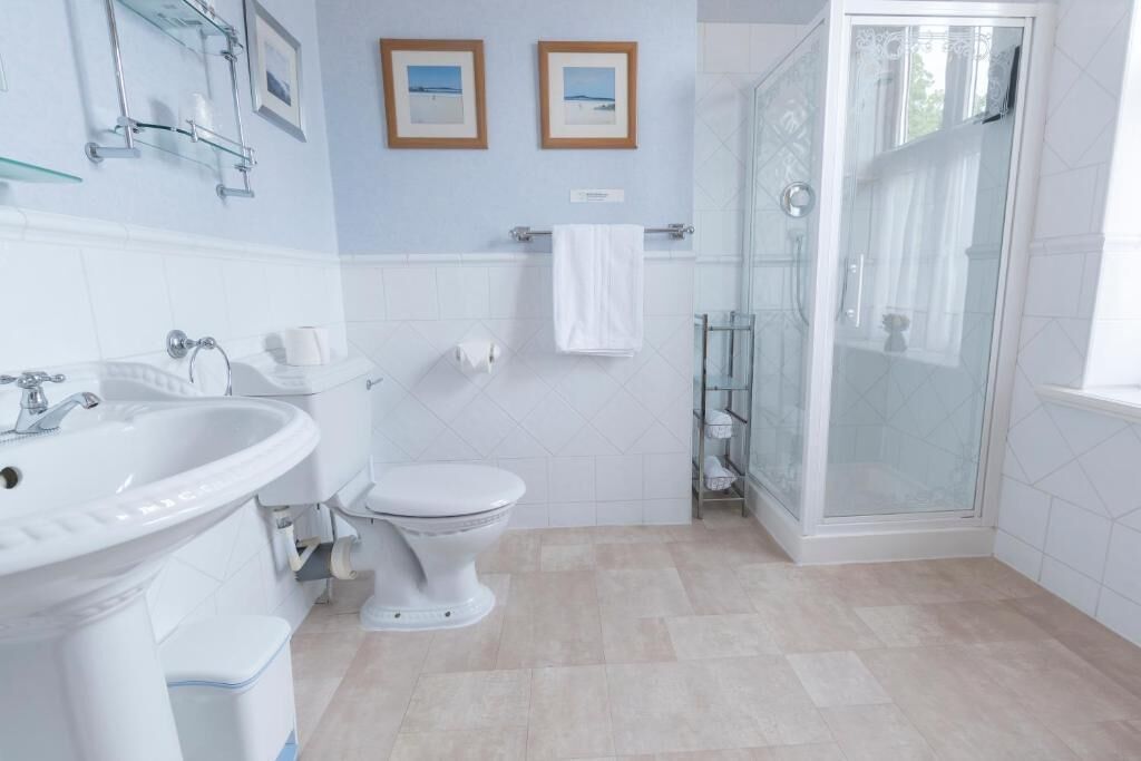 A bathroom with a sink, toilet, and glass shower enclosure.
