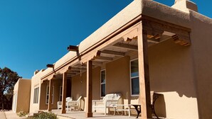 A single-story building with a covered porch, outdoor seating, and a clear blue sky. - Private and spacious home near the Plaza with mountain views! (Santa Fe)
