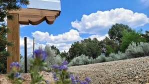 A wooden pergola with a mailbox, surrounded by gravel and sparse vegetation, under a clear sky. - Private and spacious home near the Plaza with mountain views! (Santa Fe)