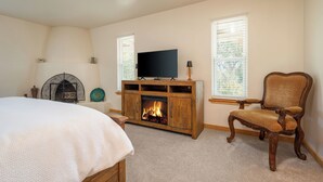 A bedroom with a bed, a fireplace, a television, and a chair. - Private and spacious home near the Plaza with mountain views! (Santa Fe)