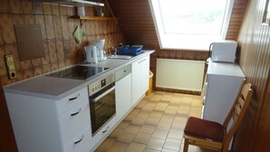 Una cocina compacta con horno integrado, cafetera y un refrigerador pequeño.