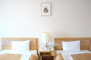 Camera d'albergo con due letti, un comodino con una lampada, una sveglia e un quadro appeso al muro.