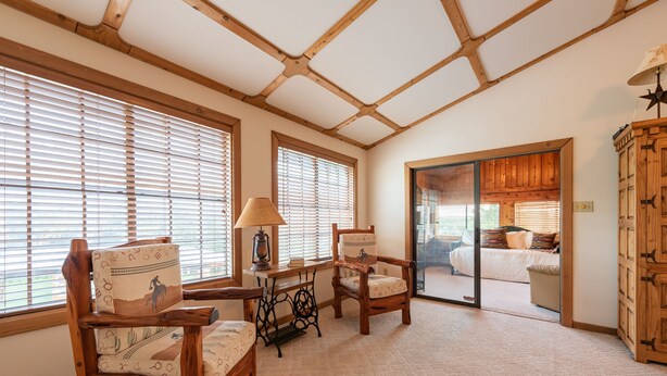 A room with wooden furniture, a sewing machine, and large windows with blinds. - Authentic Ranch Home on 650 Acres with Peace and Tranquility (Marble Falls)