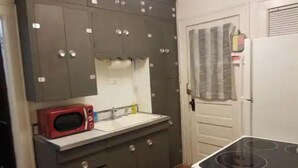 A compact kitchen with a microwave, sink, and stove. - Cozy Emerson Heights Bungalow (Indianapolis)