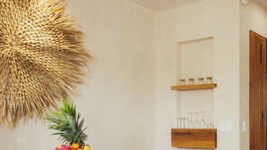 Un comedor moderno con una mesa blanca, sillas de madera y un frutero en la isla.