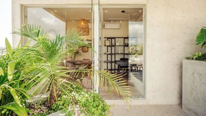 Un interior moderno con un ventanal que da a un comedor, una unidad de aire acondicionado a la vista y plantas de interior.