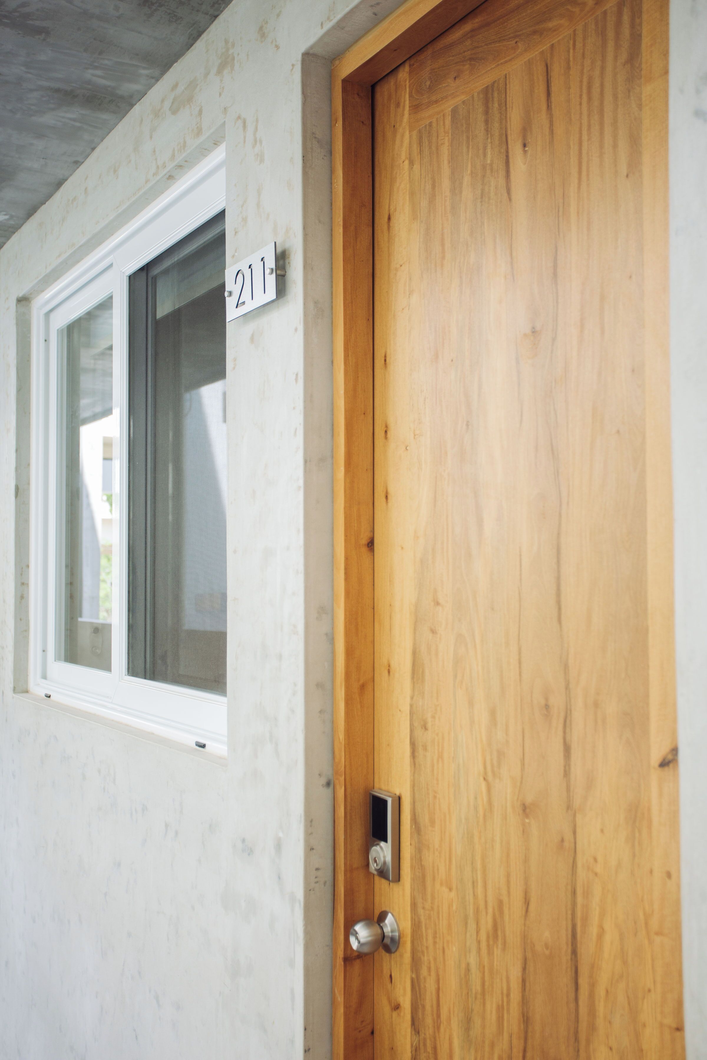 A wooden door with a number plate '211' and a window with a white frame.