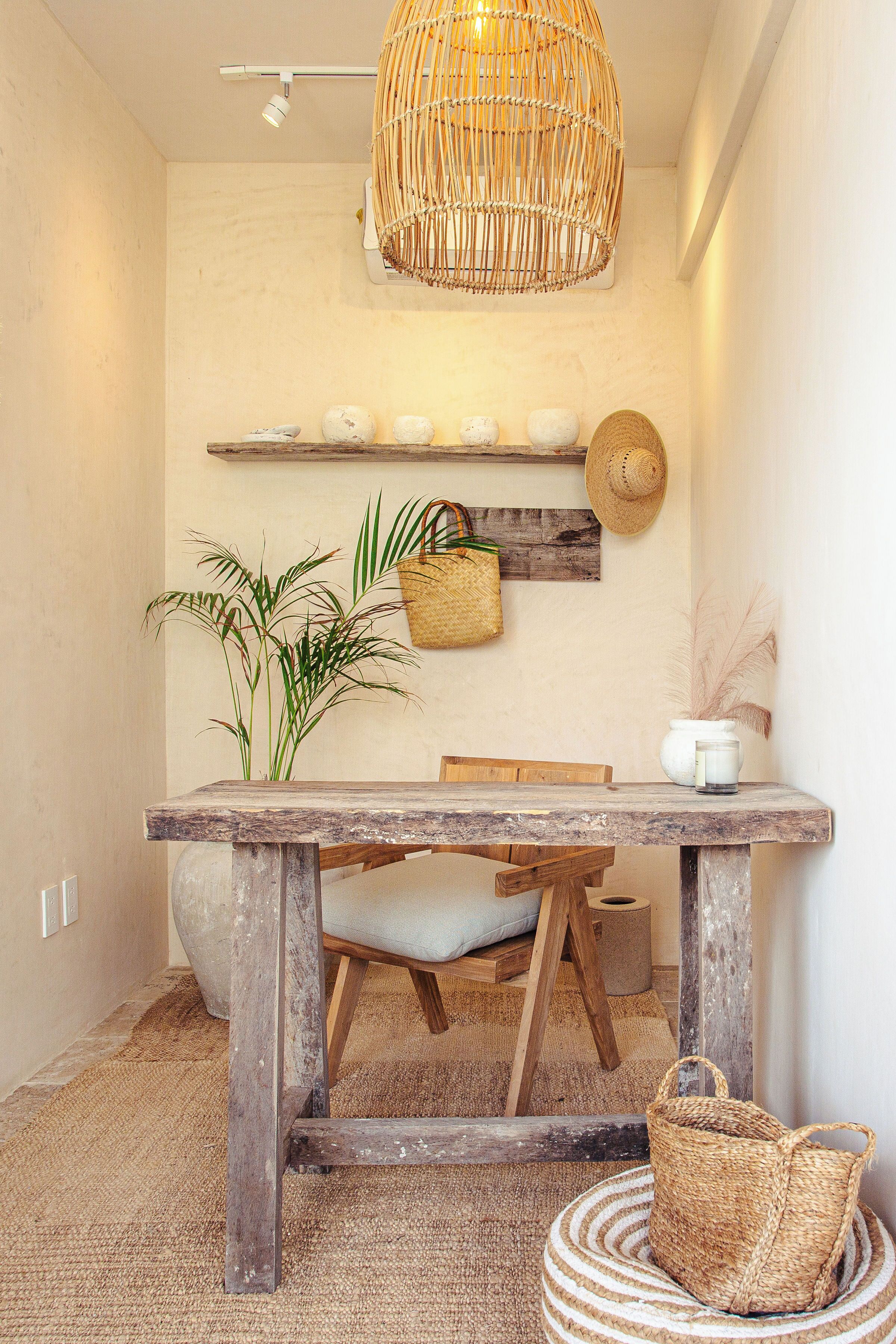 A rustic interior with a wooden table, wicker basket, and a hanging wicker light fixture.