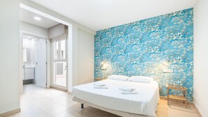 Un dormitorio con una cama grande, un papel tapiz floral azul y una mesita de noche con una lámpara.