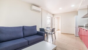 Un appartement moderne avec un canapé bleu, une table à manger et un coin cuisine doté de placards roses.