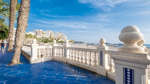 A coastal promenade with a blue tiled walkway, palm trees, and a white balustrade. - Apartamentos La Rosita Old Town A-10 (Benidorm)