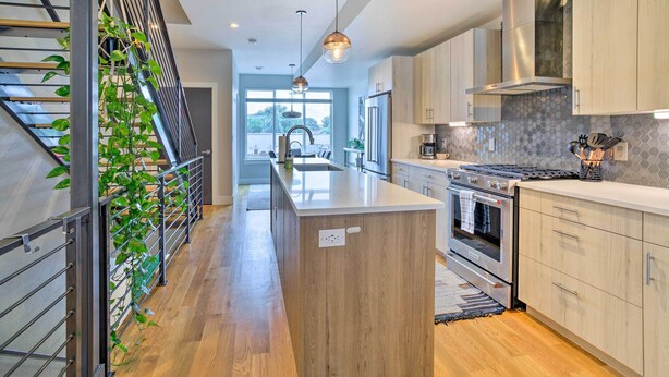 A modern kitchen with wooden cabinets, stainless steel appliances, and a central island. - City Skyline Views: Upscale Denver Townhome (Denver)