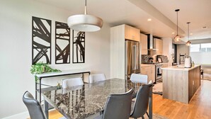 A modern kitchen with stainless steel appliances, a marble dining table, and contemporary light fixtures. - City Skyline Views: Upscale Denver Townhome (Denver)