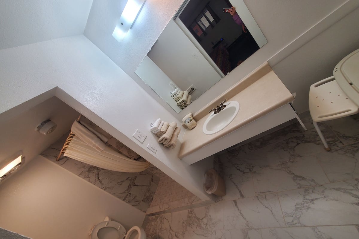 A bathroom with a toilet, sink, and a mirror.