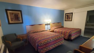 Ein Hotelzimmer mit zwei Betten, einem Schreibtisch, einem Stuhl und einem kleinen Tisch.