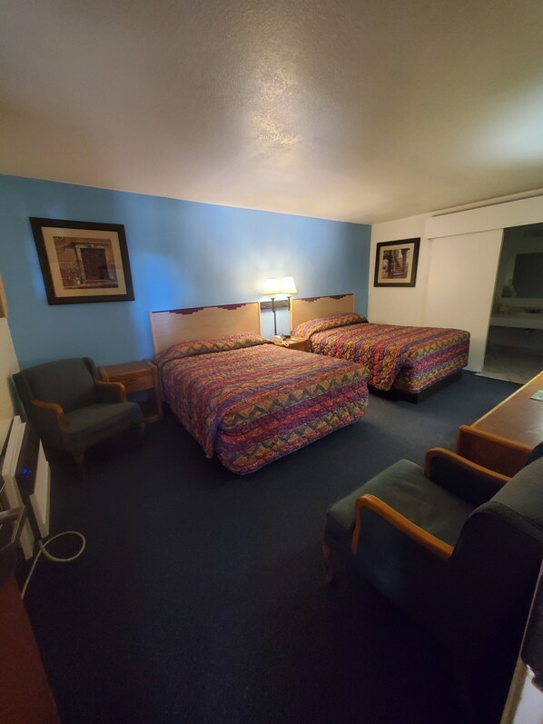 A hotel room with two beds, a desk, a chair, and a small table. - Rode Inn of Clifton (Clifton)