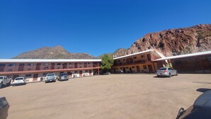 A motel with a dirt parking lot, a building with multiple rooms, and a mountainous backdrop. - Rode Inn of Clifton (Clifton)
