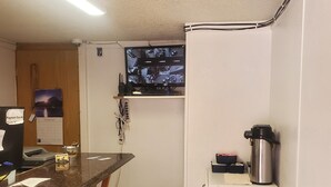 A compact kitchen with a bar area, a small trash bin, and a mounted security camera. - Rode Inn of Clifton (Clifton)
