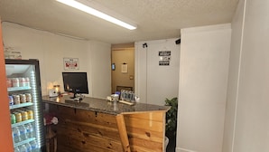 A reception area with a wooden counter, a vending machine, a flat-screen TV, and a sign on the wall. - Rode Inn of Clifton (Clifton)