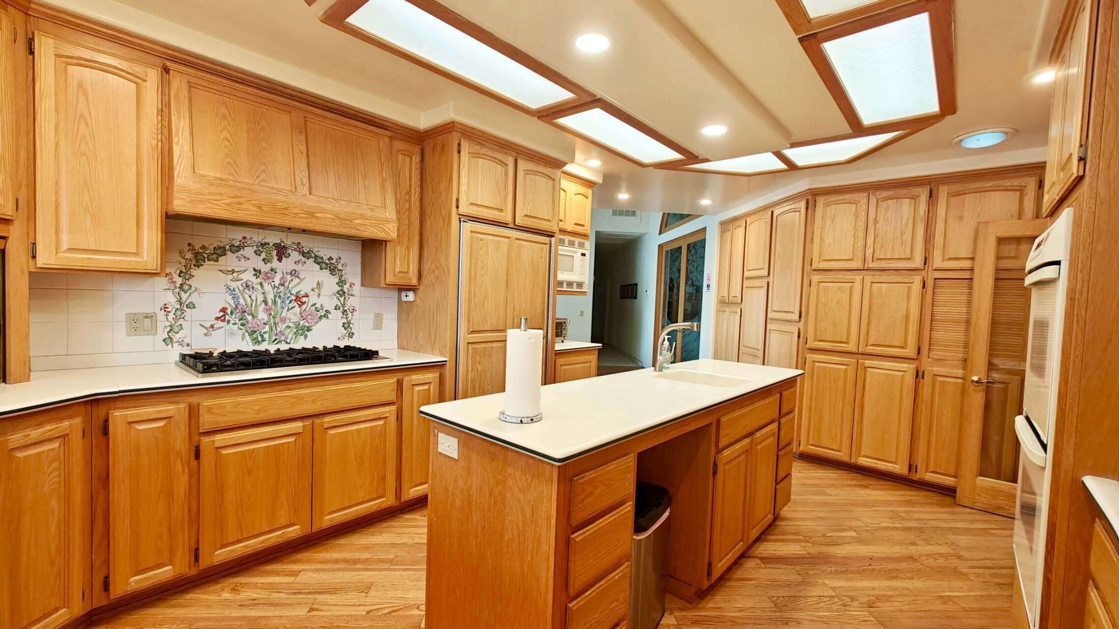 A kitchen with wooden cabinets, a central island, a microwave, and a sink.